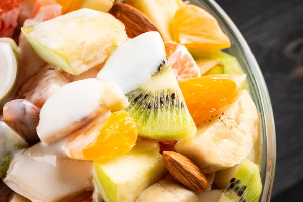Tahta arka planda bir kase sağlıklı taze meyve salatası. Üst görünüm.