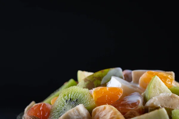 Tahta arka planda bir kase sağlıklı taze meyve salatası. Üst görünüm.