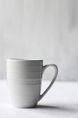 Beyaz kahve fincanı beyaz bir sırt çantasının üstünde.