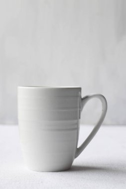 Beyaz kahve fincanı beyaz bir sırt çantasının üstünde.