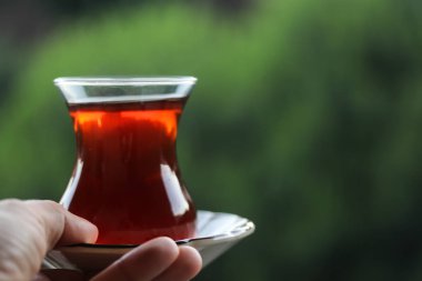 Bir bardak siyah çay, elinde bir bardak Türk çayı