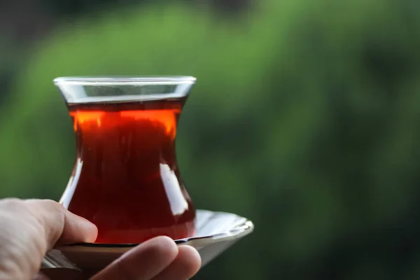 A glass of black tea, hand holding a glass of Turkish tea