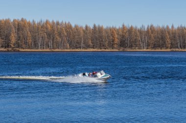 Sakin gölde, yüksek hızlı sürat teknesi turistleri hızlı bir şekilde kaydırıp insanlara mutluluk getiren,