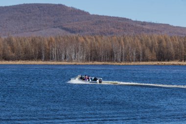 Sakin gölde, yüksek hızlı sürat teknesi turistleri hızlı bir şekilde kaydırıp insanlara mutluluk getiren,
