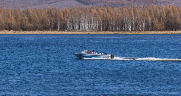 Sakin gölde, yüksek hızlı sürat teknesi turistleri hızlı bir şekilde kaydırıp insanlara mutluluk getiren,