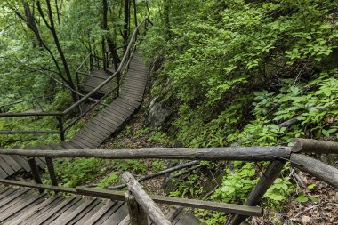 Jilin Eyaleti, Çin'de Hanging Kettle Tourist Resort ahşap tahta yolda, tahta yol dağlar tarafından ormanlar arasında inşa edilmiştir. Tahta yolda yürümek, insanların her zaman dağlara ve nehirlere entegre olduğunu gösteriyor..