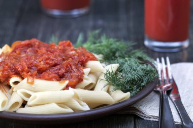 Domates, domates soslu makarna dekore edilmiş ahşap bir masa üzerine dereotu ile