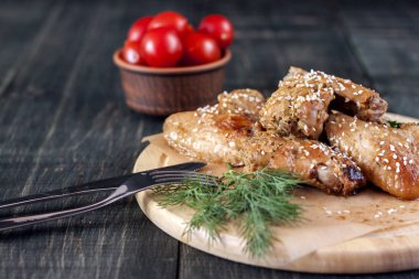 Kızarmış tavuk kanadı bir rustik hizmet yönetim kurulu, siyah ahşap zemin üzerinde