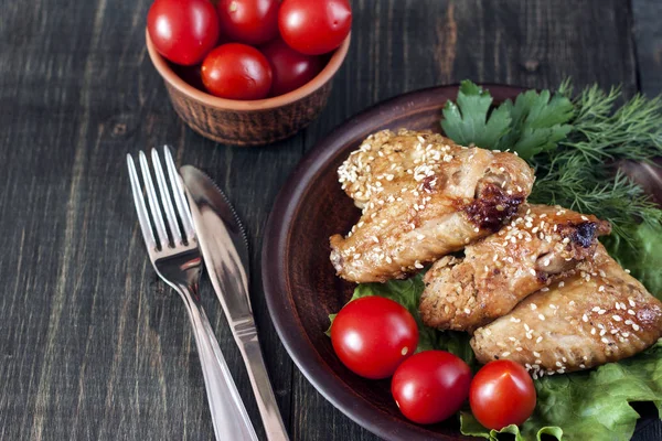 Fried chicken wings on a rustic serving board, on a black wooden background