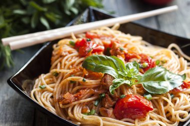 Spagetti domates soslu tavuk, domates, maydanoz üzerinde ahşap bir masa ile dekore edilmiş