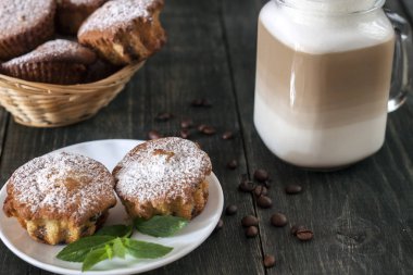 Ahşap bir masa üzerinde bir fincan kahve ile cupcakes vardır