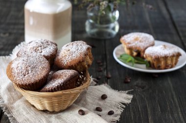 Ahşap bir masa üzerinde bir fincan kahve ile cupcakes vardır