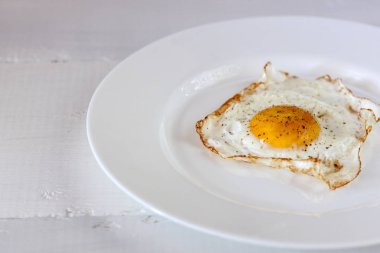 Kızarmış yumurta bir ahşap beyaz masa üzerinde beyaz bir plaka üzerinde