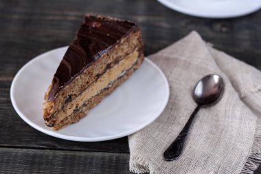 Ahşap bir masa üzerinde bir dilim pasta beyaz bir plaka üzerinde olduğunu