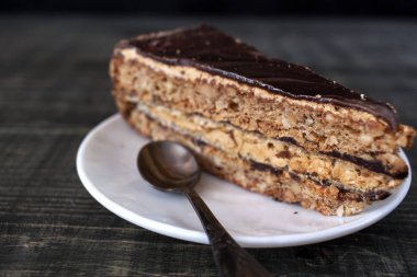 Ahşap bir masa üzerinde bir dilim pasta beyaz bir plaka üzerinde olduğunu