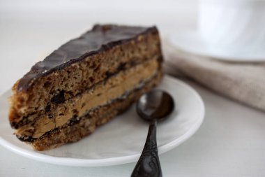 Ahşap bir masa üzerinde bir dilim pasta beyaz bir plaka üzerinde olduğunu