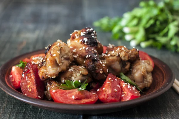 Fried chicken wings on a rustic serving board, on a black wooden background