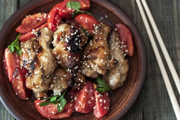 Fried chicken wings on a rustic serving board, on a black wooden background