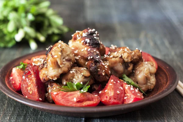 Fried chicken wings on a rustic serving board, on a black wooden background