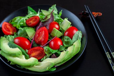 Diyet karanlık bir arka plan üzerinde siyah bir plaka üzerinde avokado salatası.
