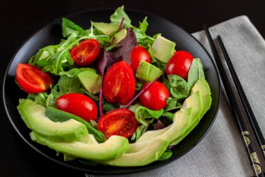Diyet karanlık bir arka plan üzerinde siyah bir plaka üzerinde avokado salatası.