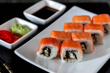 Philadelphia suşi rulo yapılmış taze somon, avokado ve krem peynir ile içinde mürekkep balığı mürekkep siyah pirinç ile. Geleneksel Japon mutfağı. Asya gıda