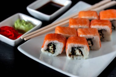 Philadelphia suşi rulo yapılmış taze somon, avokado ve krem peynir ile içinde mürekkep balığı mürekkep siyah pirinç ile. Geleneksel Japon mutfağı. Asya gıda