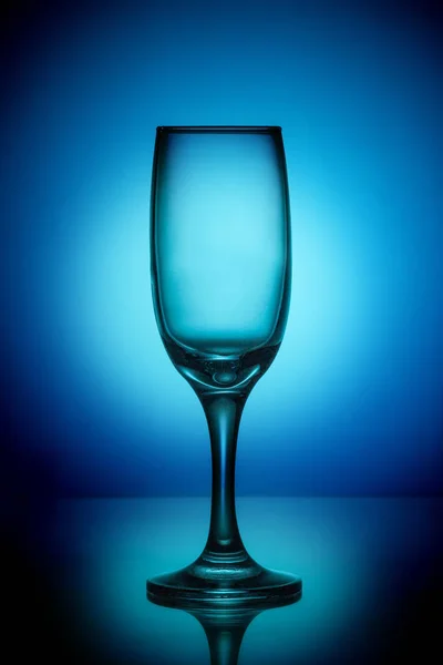 중앙에 밝은 반점 가진 파란 배경에 빈 와인 잔 — 스톡 사진
