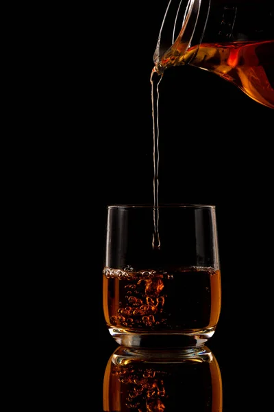 Brandy öntenek a pohárba a fekete háttér — Stock Fotó