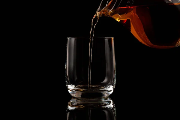Brandy öntenek a pohárba a fekete háttér — Stock Fotó