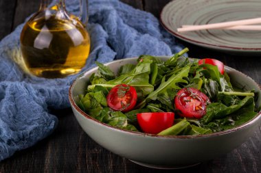 Siyah ahşap masada domates, arugula ve ıspanak salatası
