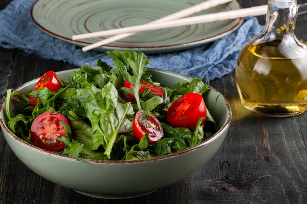 Insalata con pomodori, rucola e spinaci su un tavolo di legno nero — Foto Stock