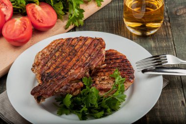 ahşap bir masa üzerinde beyaz bir çanak üzerinde otlar ile kızarmış domuz eti bir parça, closeup görünümü