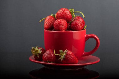 Siyah cam bir masa üzerinde çilek ile bir fincan