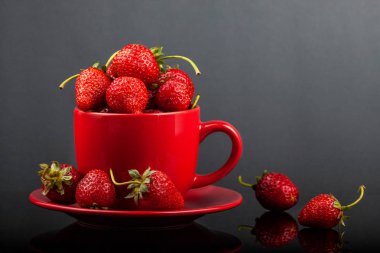 Siyah cam bir masa üzerinde çilek ile bir fincan