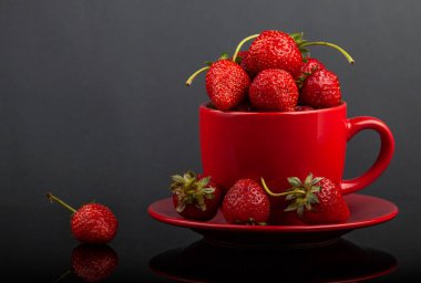 Siyah cam bir masa üzerinde çilek ile bir fincan