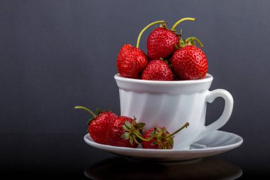 Siyah cam bir masa üzerinde çilek ile bir fincan