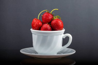 Siyah cam bir masa üzerinde çilek ile bir fincan