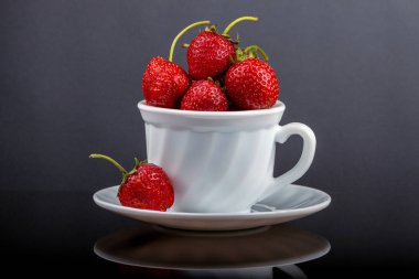 Siyah cam bir masa üzerinde çilek ile bir fincan