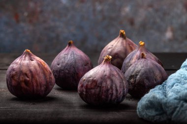 Taze incir siyah ahşap bir masanın üzerinde yatıyor. Güzel mavi incir meyve yakın