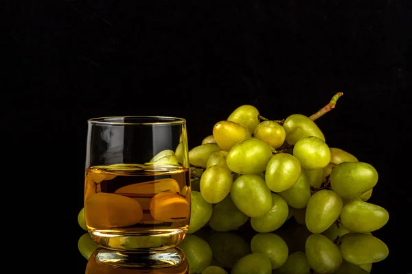 Два бокала белого вина и гроздь винограда, изолированного на черном — стоковое фото