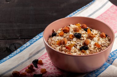 Kuru üzümlü yulaf ezmesi ve siyah ahşap bir masada seramik kasede fındık.