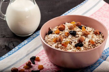 Kuru üzümlü yulaf ezmesi ve siyah ahşap bir masada seramik kasede fındık.