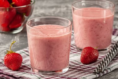 Gri arka planda sütlü çilekli smoothie, kahvaltıda sağlıklı beslenme ve atıştırmalıklar