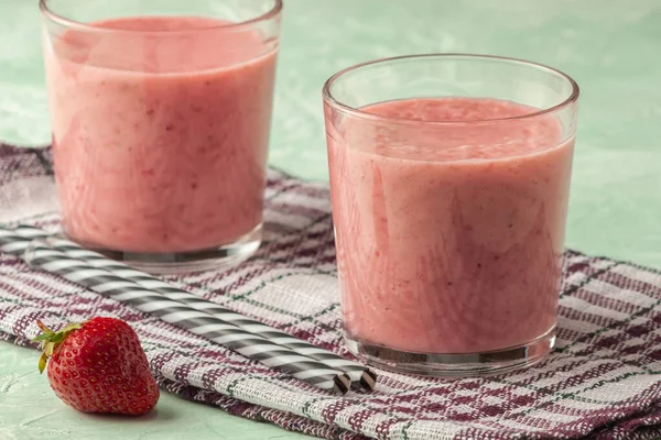 Smoothie aux fraises avec lait dans un verre sur fond vert, alimentation saine pour le petit déjeuner et collations — Photo