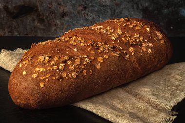 Kepekli taze ekmek, ayçiçeği tohumu ve masada yulaf ezmesi.