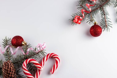 Firavun ağacı dalları, beyaz arka planda kırmızı süslemeler. Noel kompozisyonu. Noel, kış, yeni yıl konsepti. Düz konum, üst görünüm, kopyalama alanı