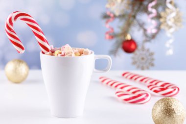 Beyaz bir masada latteli bir bardakta şekerlemeler.