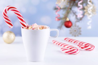 Beyaz bir masada latteli bir bardakta şekerlemeler.