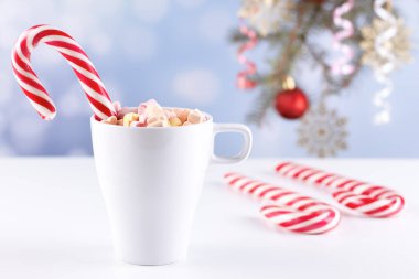 Beyaz bir masada latteli bir bardakta şekerlemeler.